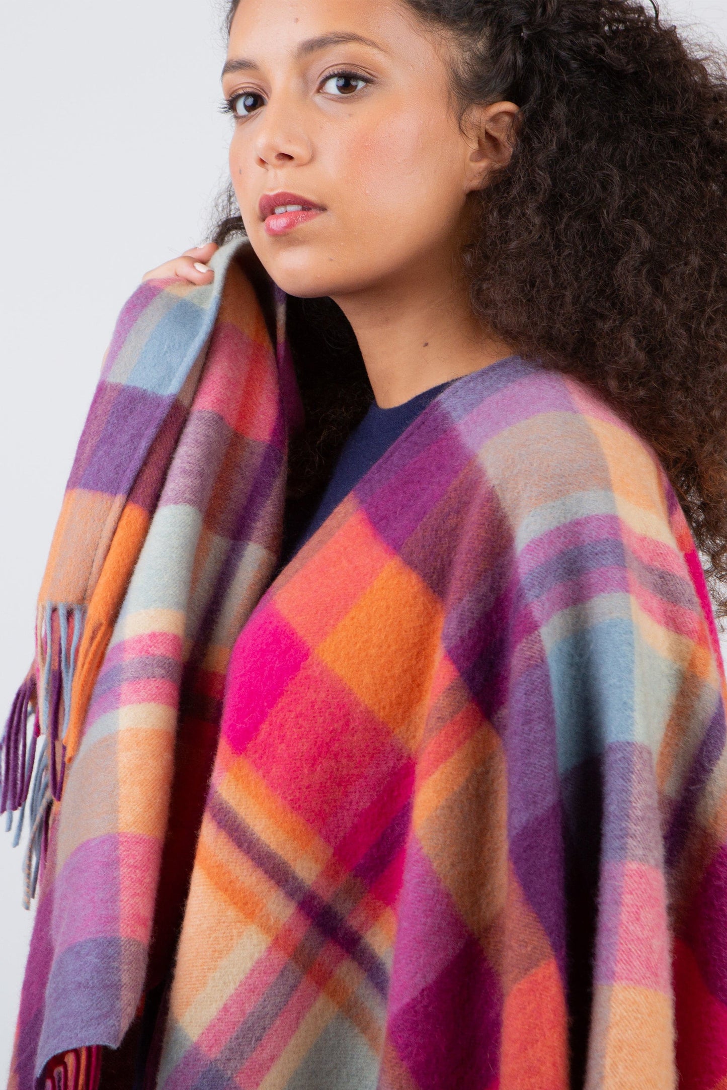 Square Check Lambswool Wrap in Orient Ginger draped over shoulders, showing vibrant pink, orange, purple, and blue plaid with fringed edges