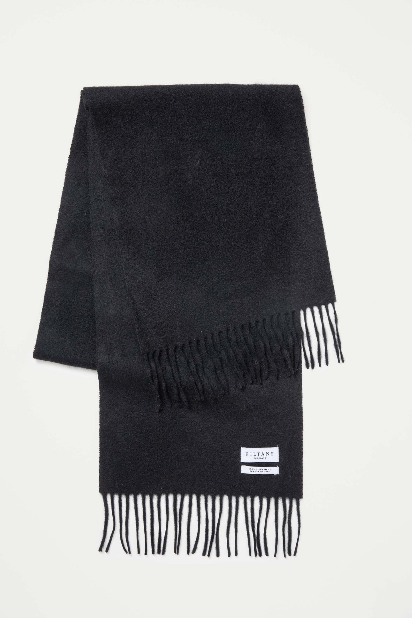 Kiltane Scotland Solid Cashmere Scarf in black, folded flat showing soft texture, fringed ends, and brand label