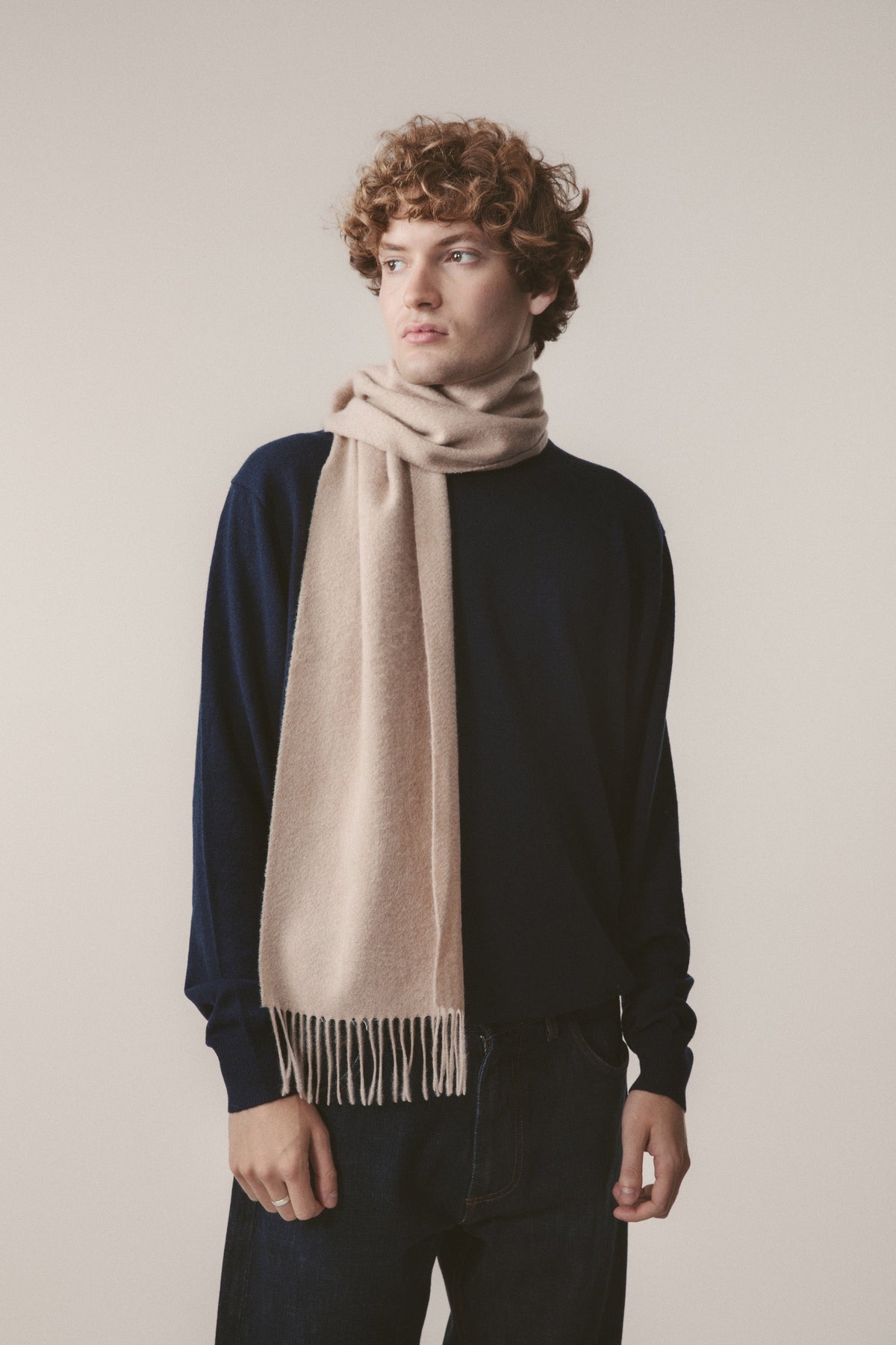 Solid Cashmere Scarf in Vicuna worn loosely wrapped around the neck, showing soft beige tone and fringed ends