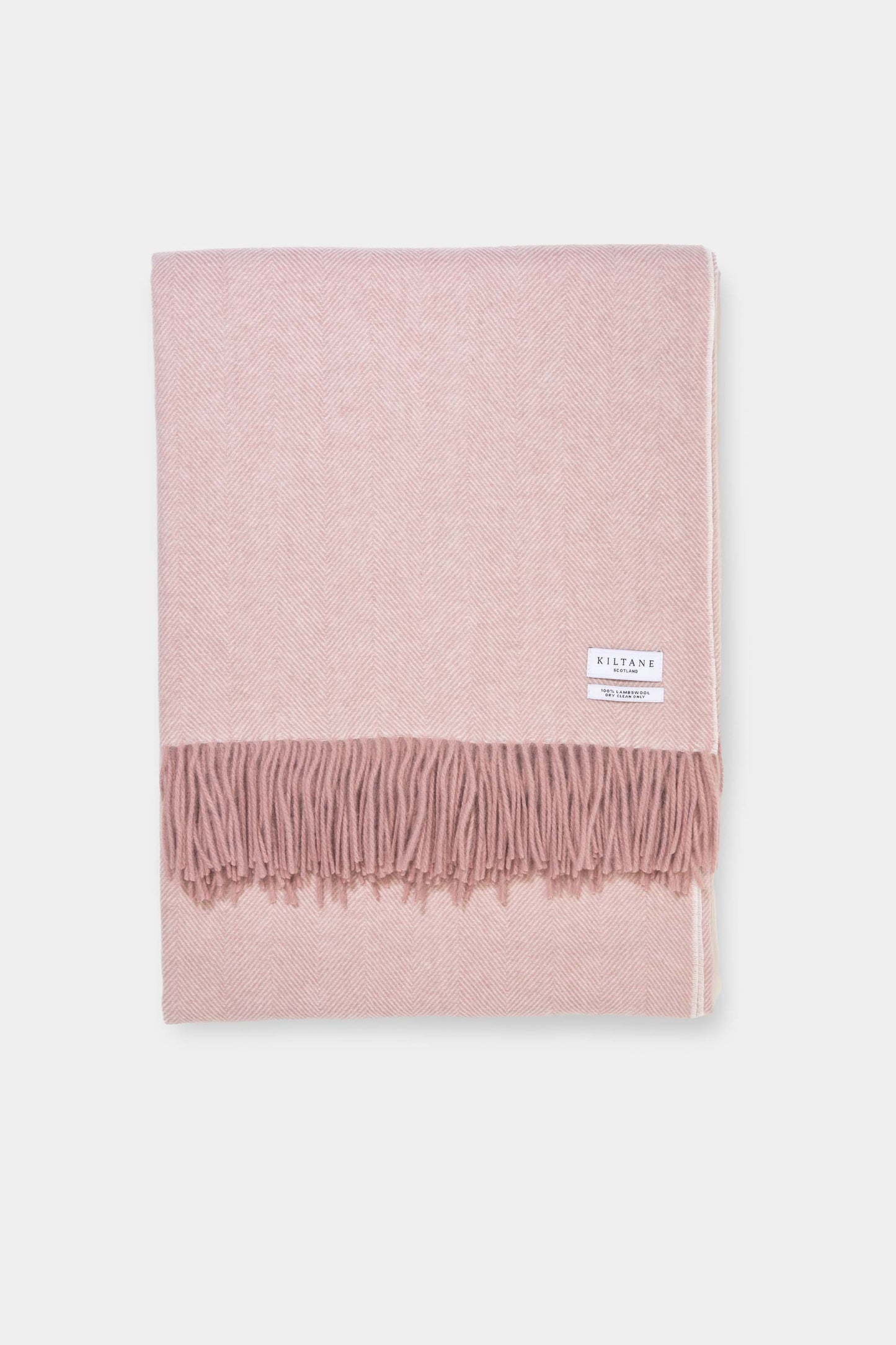 Kiltane Herringbone Lambswool Throw in Cameo Rose, folded flat showing soft pink herringbone weave and fringed edge