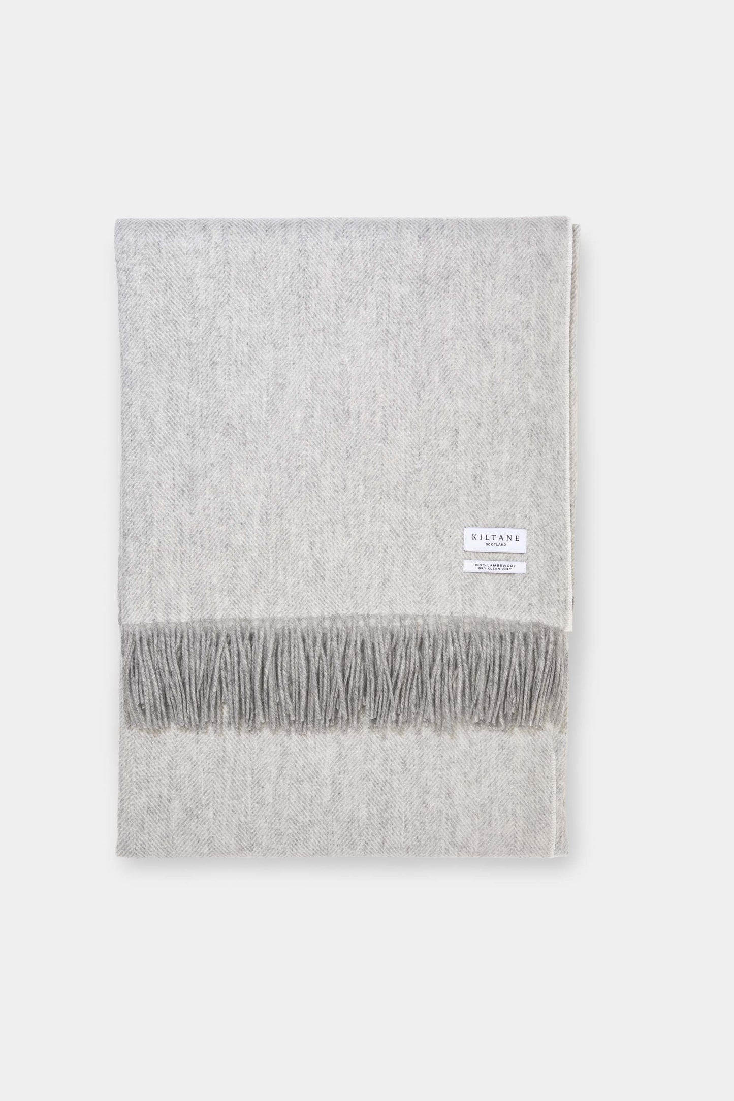 Kiltane Herringbone Lambswool Throw in Silver Grey, neatly folded showing herringbone weave pattern and fringed edge