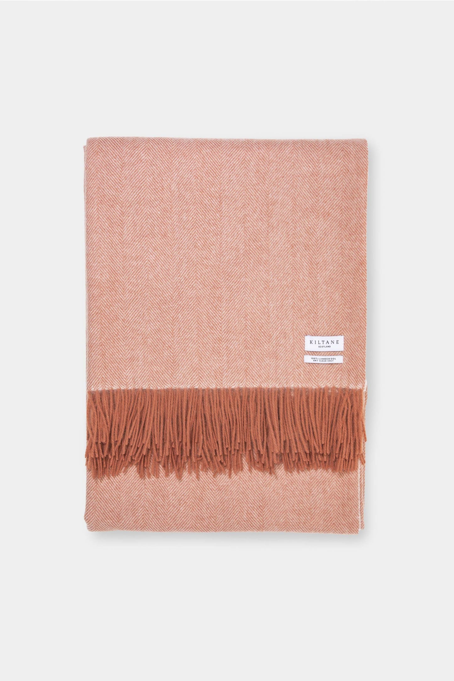Kiltane Herringbone Lambswool Throw in Spice, folded to show warm terracotta herringbone weave and fringed edge
