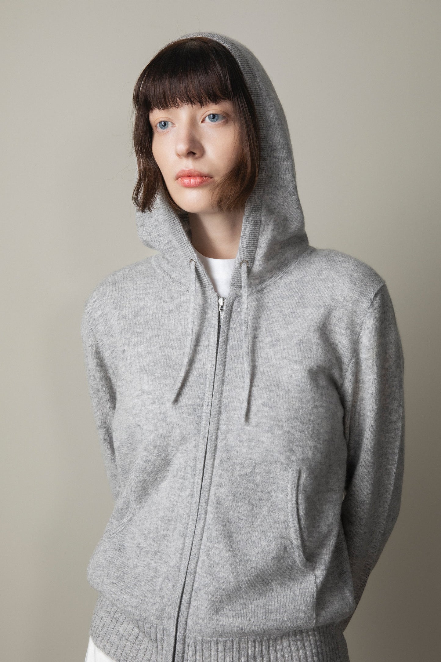 Unisex Cashmere Zip Hoodie in light grey, worn with hood up showing soft knit texture, full zip front, and kangaroo pocket
