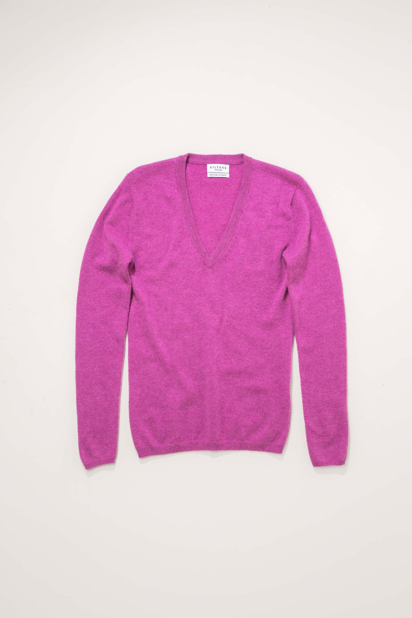 Kiltane Women's Cashmere V Neck Jumper in Raspberry laid flat, showing deep V-neckline and long sleeves
