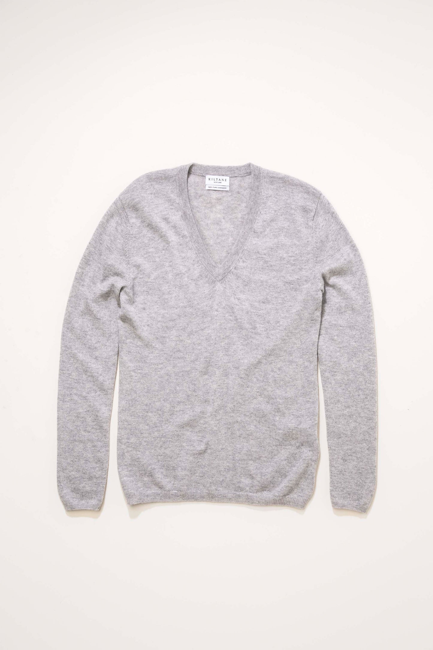 Kiltane Women's Cashmere V Neck Jumper in light grey laid flat, showing full front with ribbed V-neckline and long sleeves