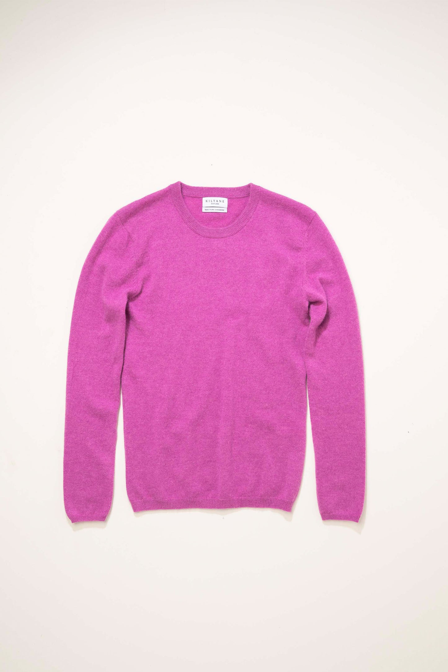 Kiltane Women's Cashmere Crew Neck Jumper in Raspberry laid flat, showing front view with ribbed cuffs and neckline