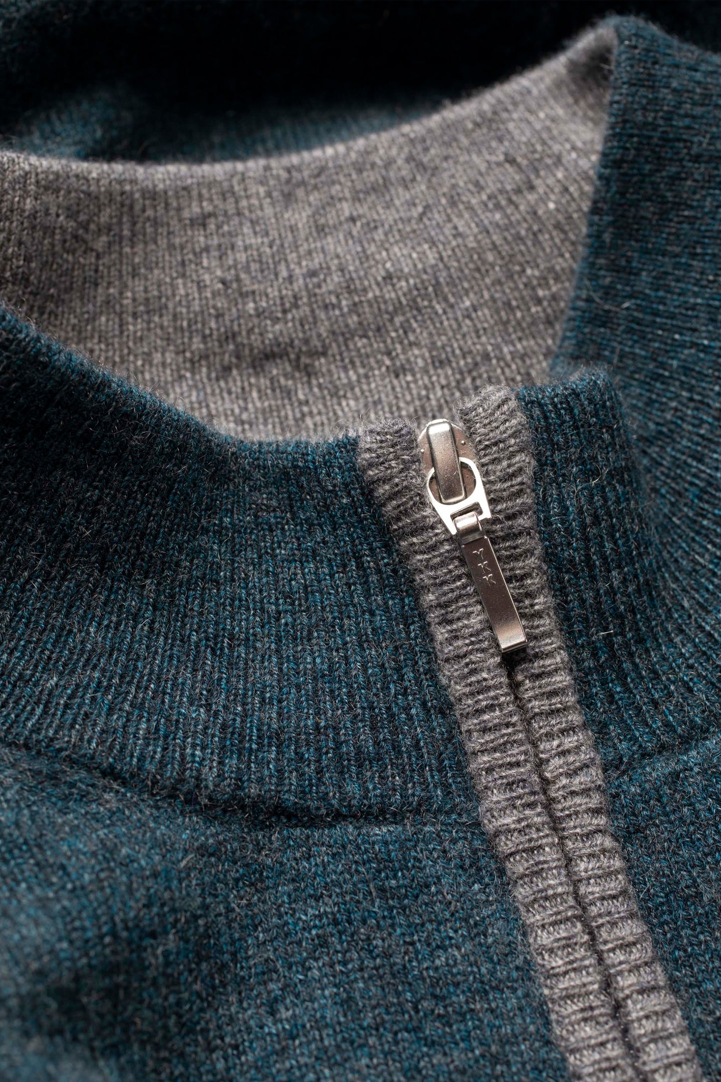 Close-up of Men's Half Zip Jumper neckline showing silver zipper pull with grey contrast trim against teal green cashmere knit