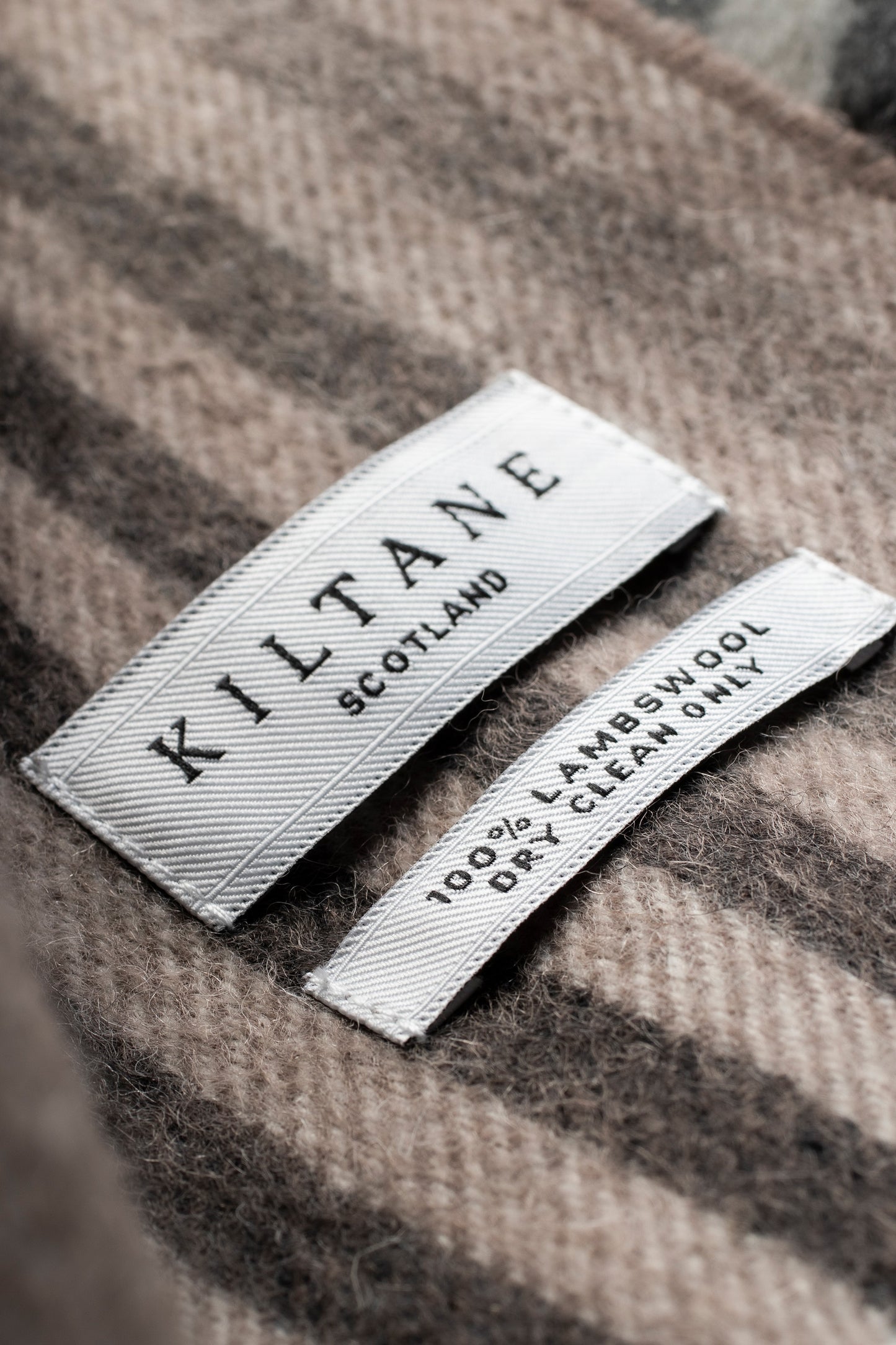 Close-up of Kiltane Scotland label on Contemporary Check Lambswool Scarf showing 100% lambswool dry clean only care tag