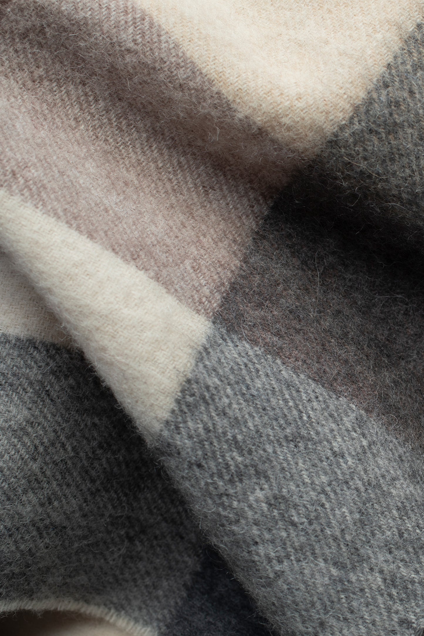 Close-up of Checkers Lambswool Scarf in Natural showing soft herringbone weave texture in cream, taupe, and charcoal tones