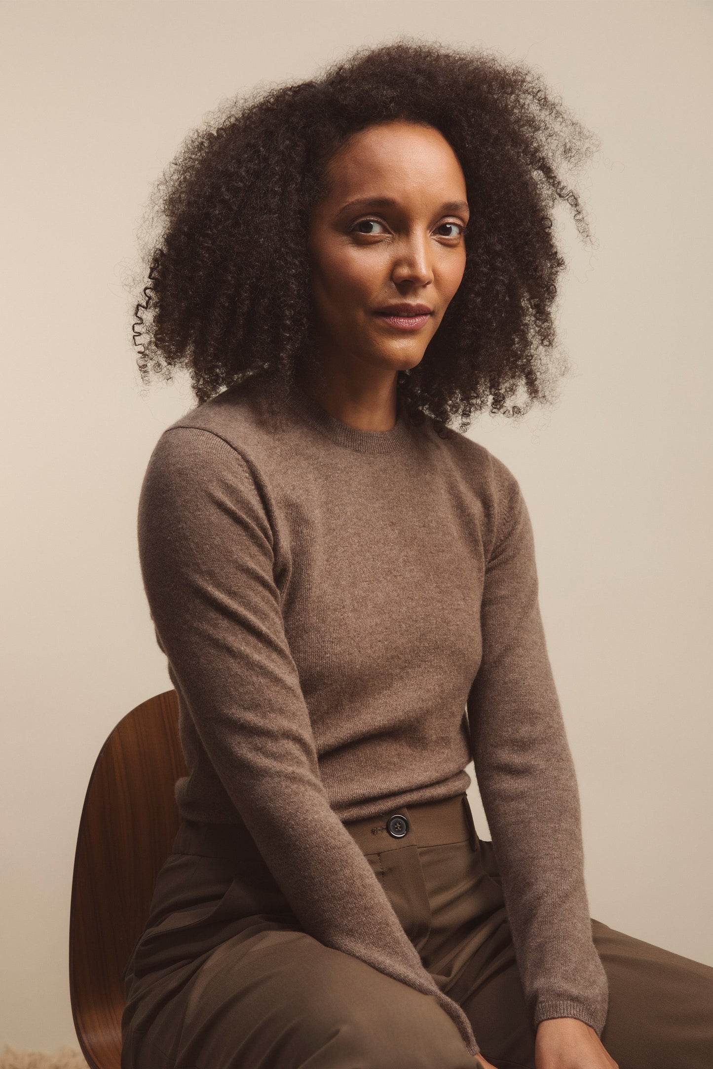 Women's Cashmere Crew Neck Jumper in Squirrel, a warm brown slim-fit knit with ribbed neckline, styled seated