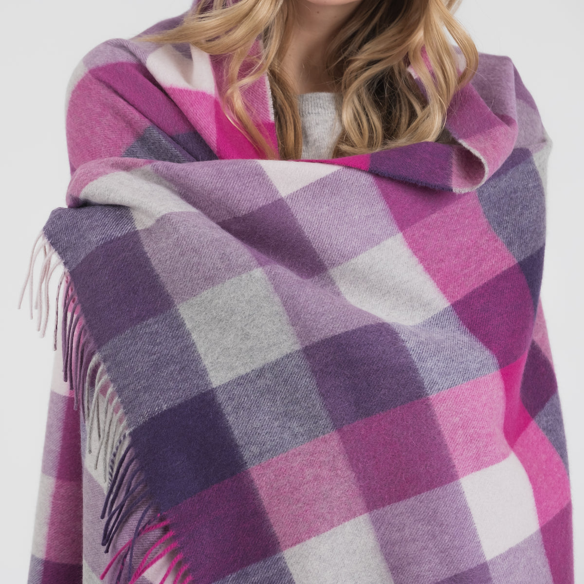 5 Square Check Cashmere Stole in Purple worn wrapped around shoulders, showing check pattern and fringed edges