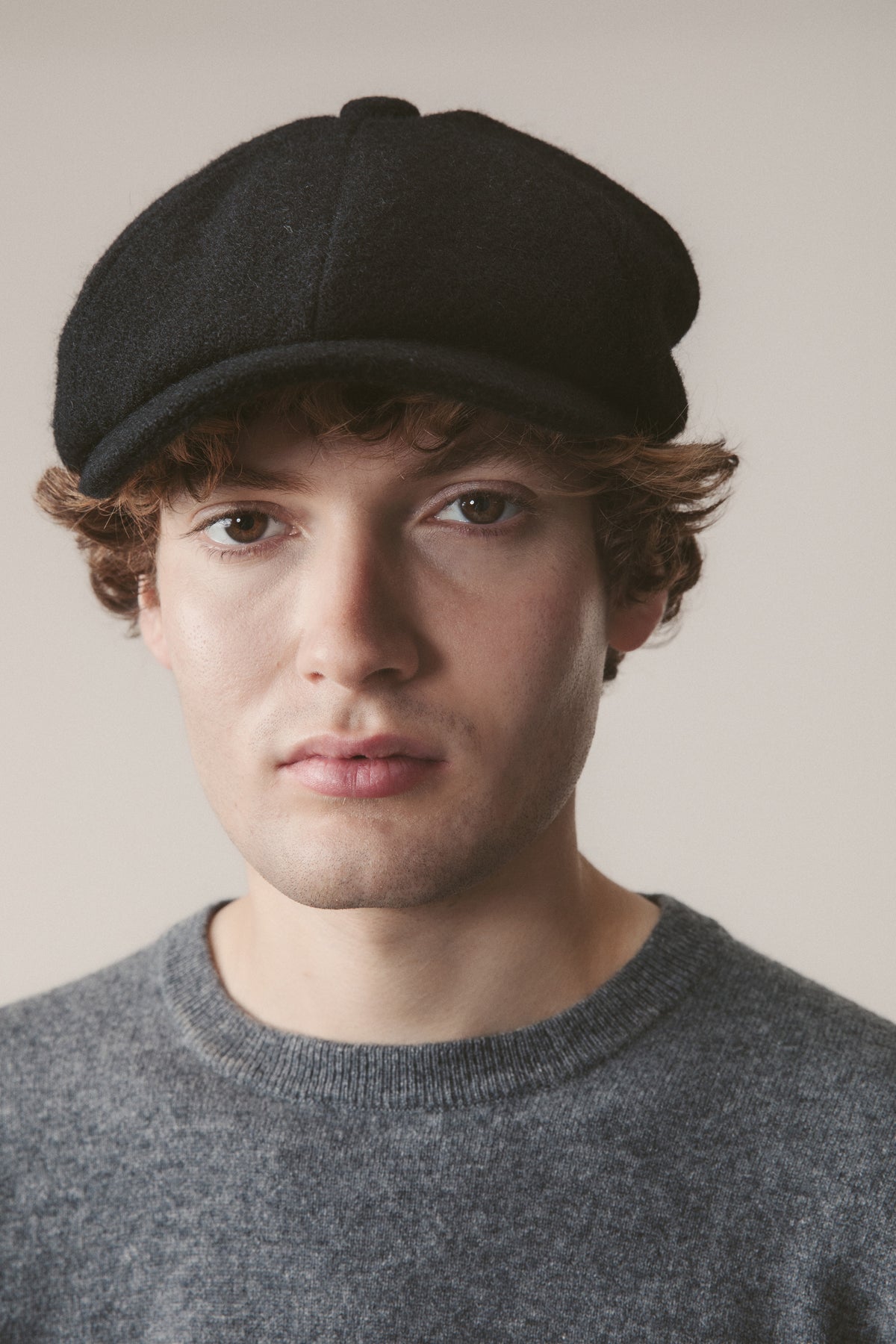 Harris Tweed Carloway Hat in plain black twill worn by model, front-facing view showing the structured newsboy silhouette