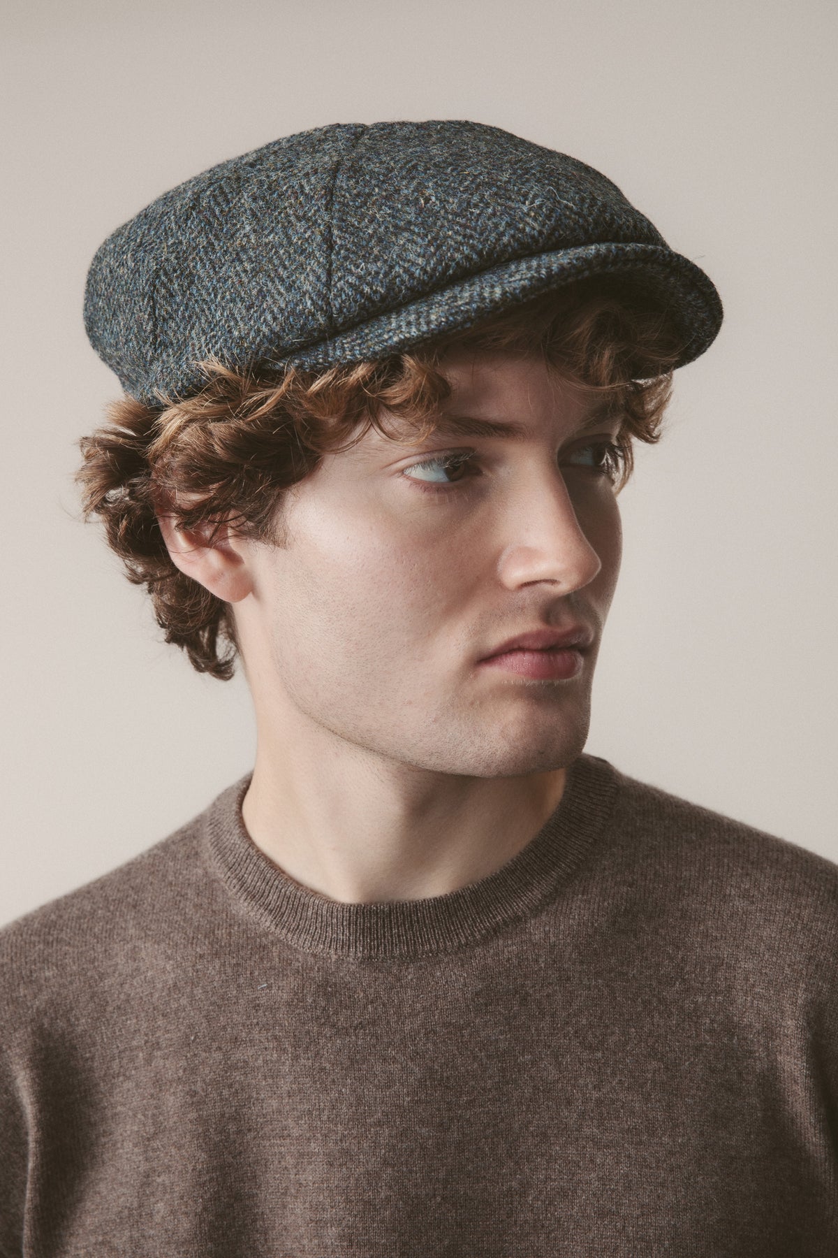 Harris Tweed Carloway Hat in Blue Mix Herringbone worn by model, three-quarter front view showing the panelled newsboy crown