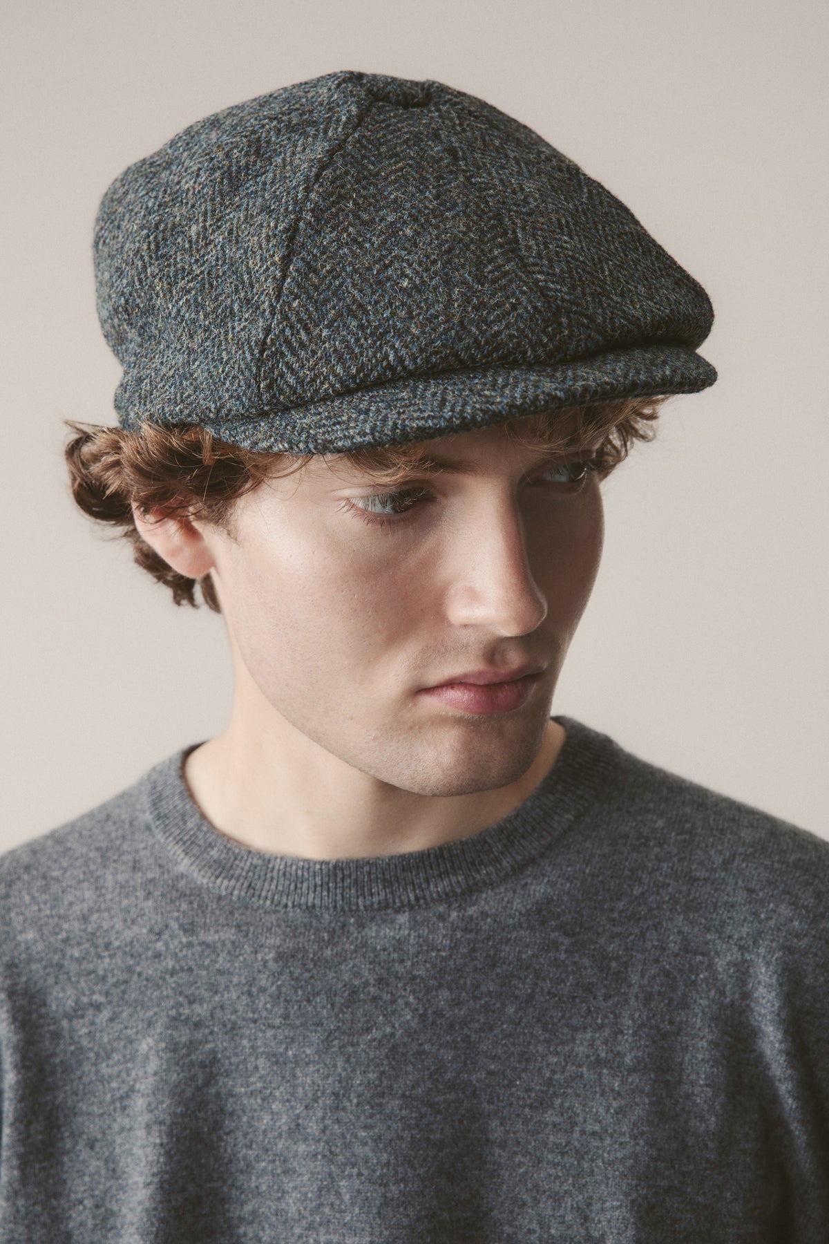 Harris Tweed Carloway Hat in Blue Mix Herringbone worn by model, front-angled view showing panelled crown and short brim