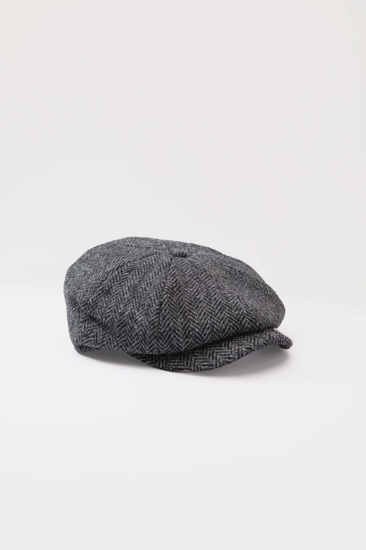 Harris Tweed Carloway Hat in charcoal herringbone, three-quarter view showing panelled crown and short brim