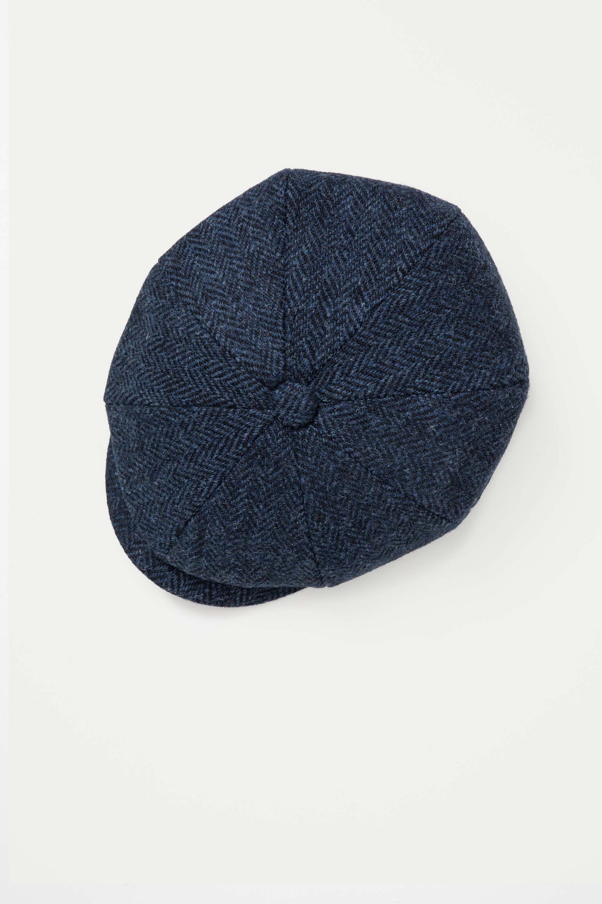 Harris Tweed Carloway Hat in dark navy blue herringbone, top-down view showing panelled crown and centre button detail