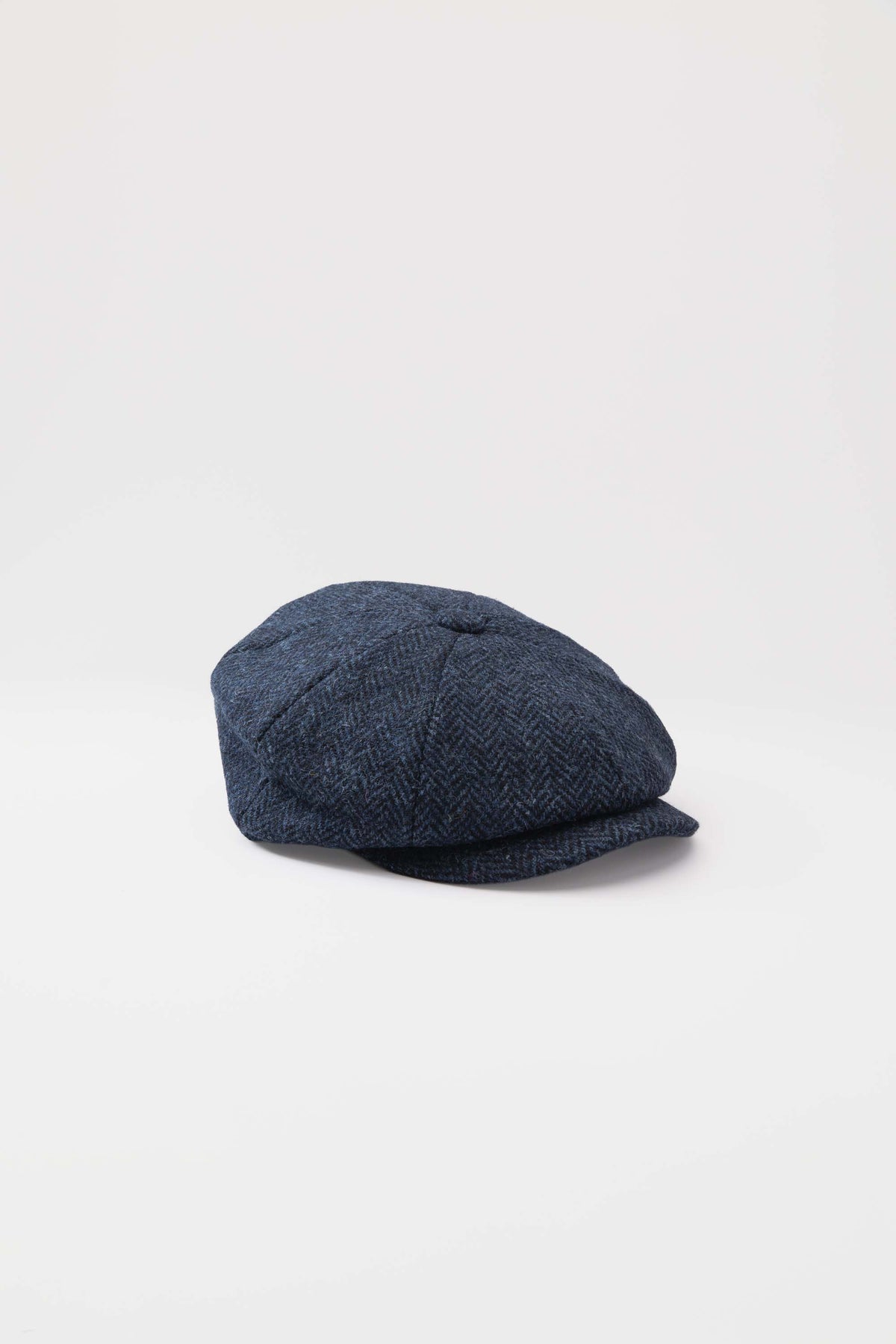 Harris Tweed Carloway Hat in dark navy blue herringbone, three-quarter front view showing eight-panel crown and short brim