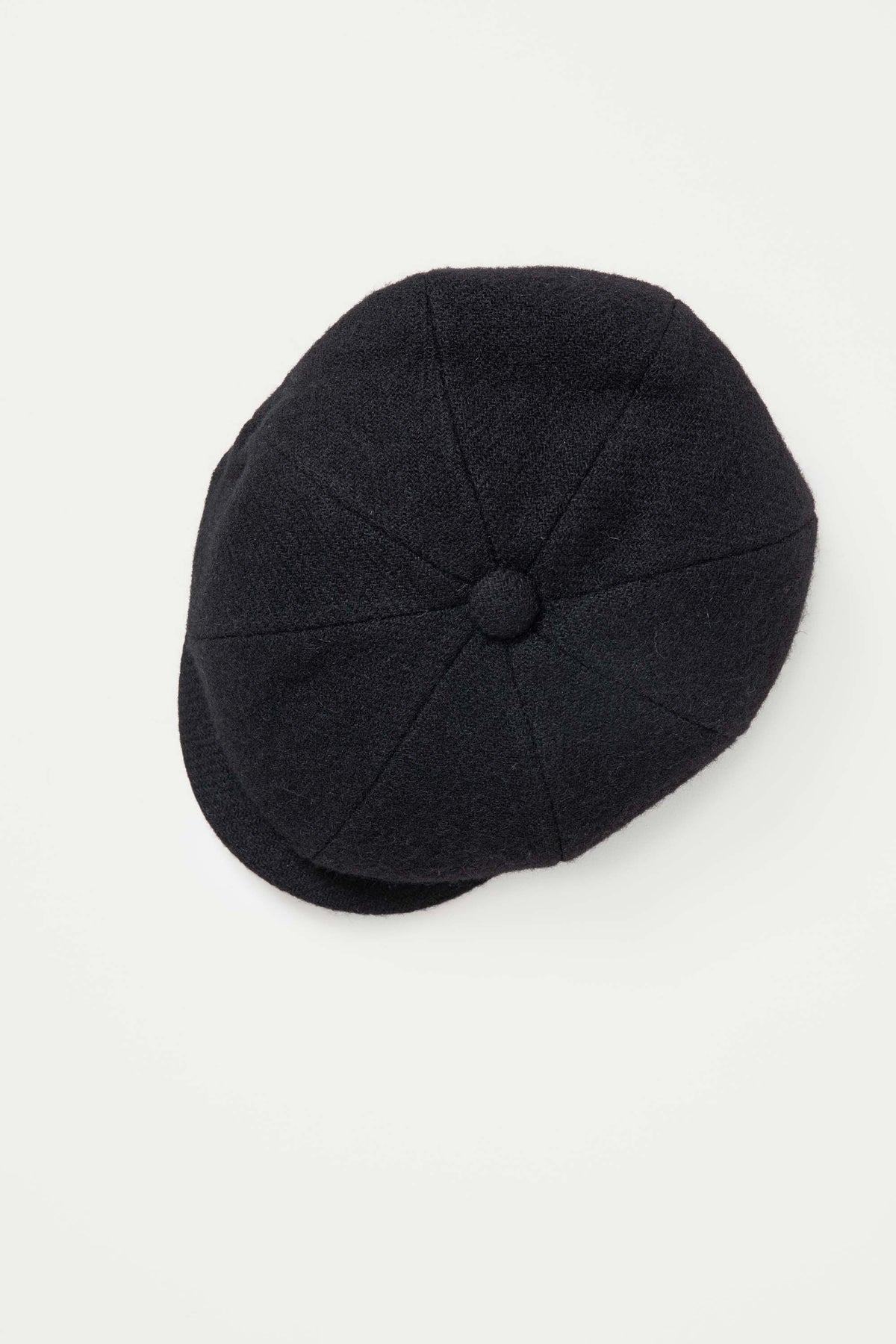 Top-down view of the Harris Tweed Carloway Hat in plain black twill showing eight-panel crown and covered button detail
