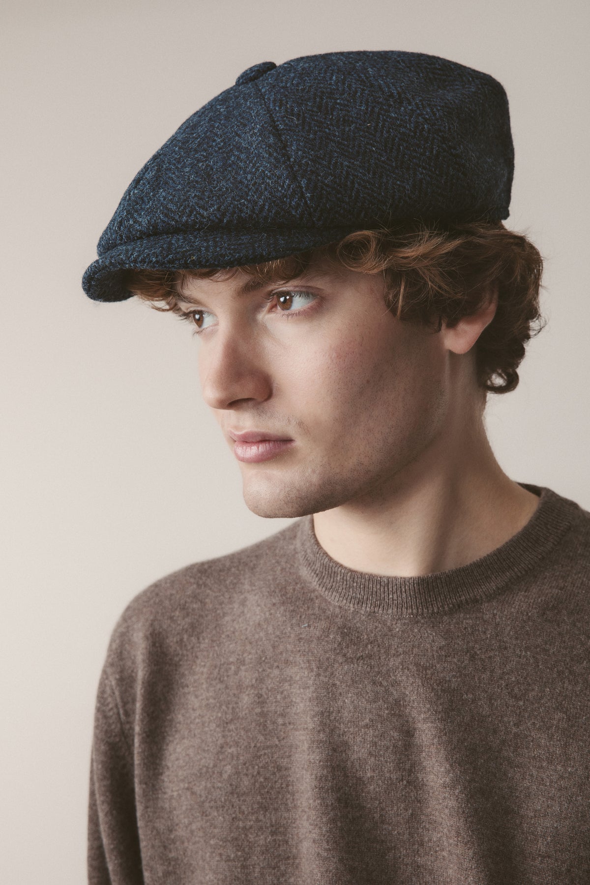 Harris Tweed Carloway Hat in dark navy blue herringbone worn by model, three-quarter profile view showing fit and brim shape