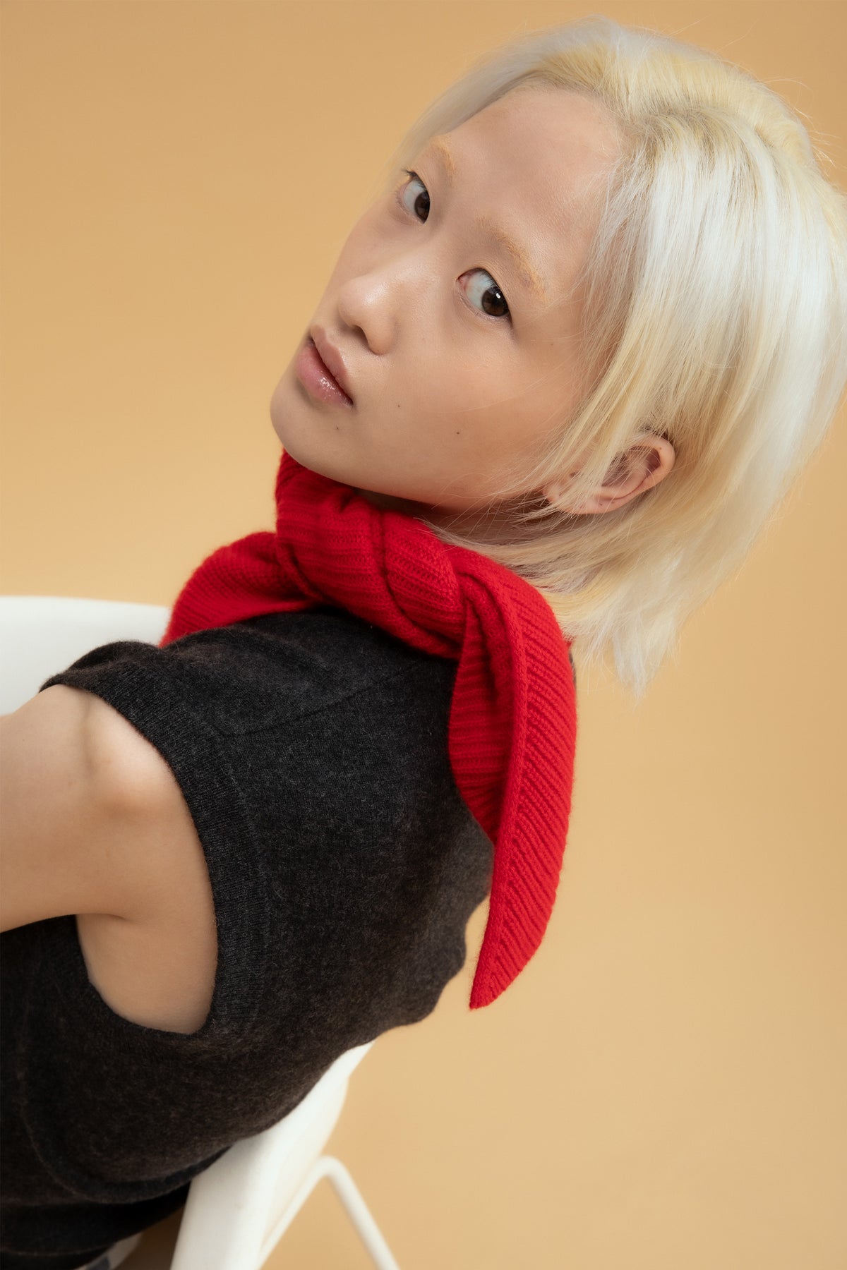 Knitted Cashmere Neck Tie in red styled knotted at the neck, paired with a charcoal sleeveless knit top