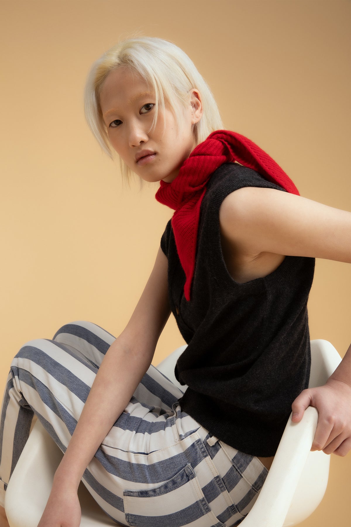 Knitted Cashmere Neck Tie in red styled draped over shoulders, paired with a black sleeveless top and striped trousers