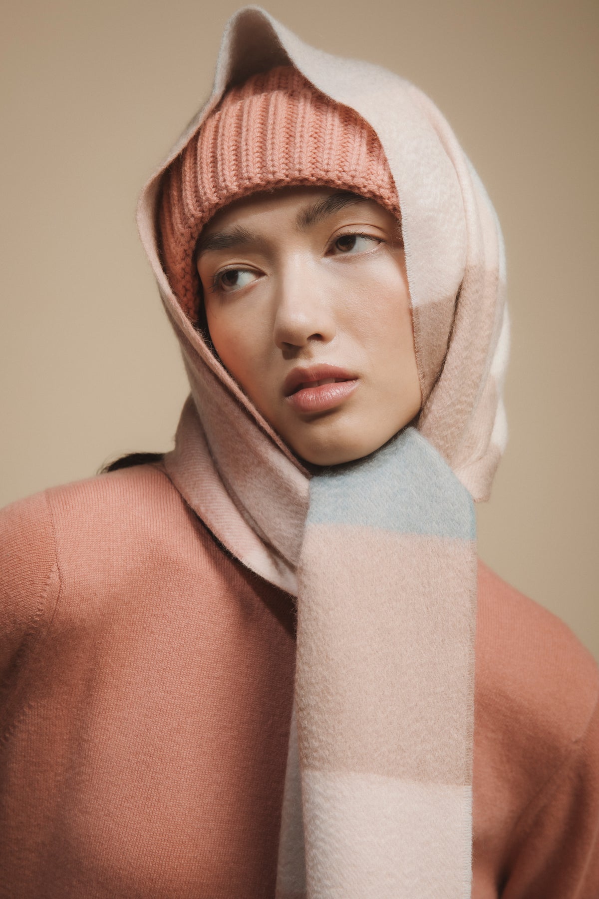 3 Square Check Cashmere Wide Scarf in Seashell worn wrapped over head, showing pink, cream, and pale blue check pattern