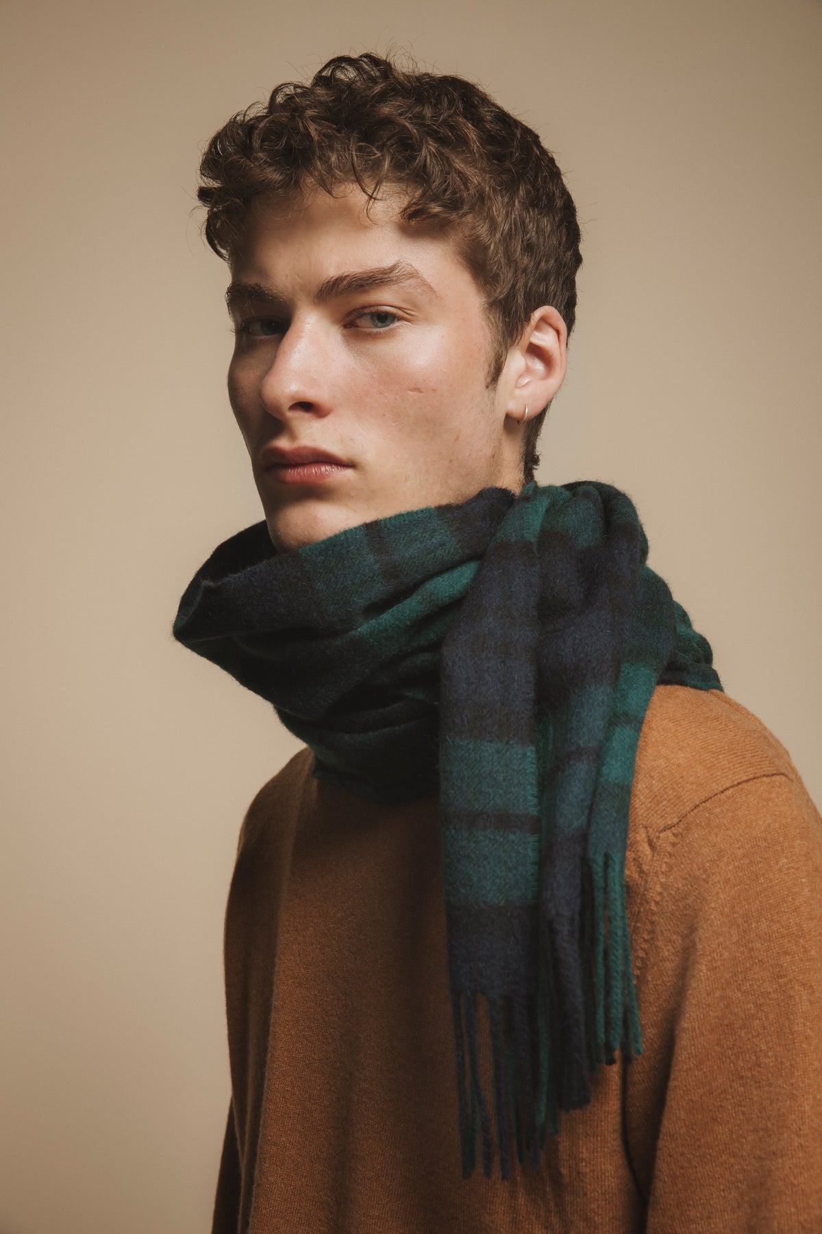 Made in Scotland Heritage Cashmere Wide Scarf in Blackwatch tartan worn wrapped snugly around the neck, showing green and navy plaid with fringed ends