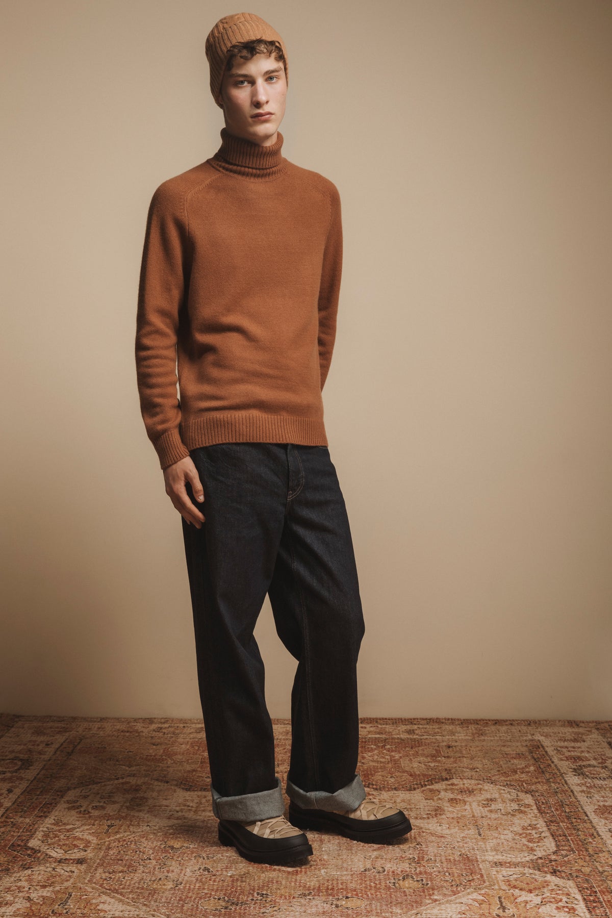 Cashmere Cable Beanie in camel worn by male model styled with a tonal turtleneck sweater and dark denim