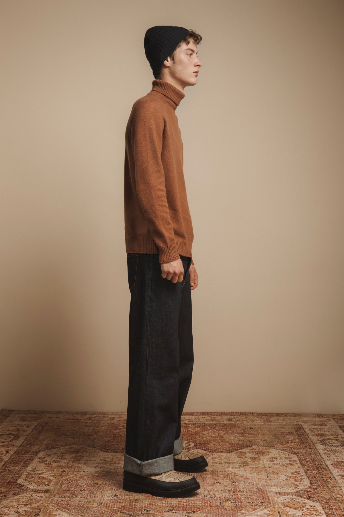Cashmere Cable Beanie in Dark Navy shown in side profile on model, paired with camel turtleneck and dark jeans