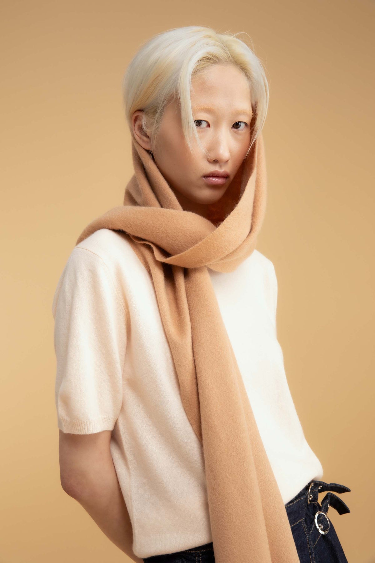 Solid Cashmere Wide Scarf in Warm Camel wrapped loosely around the neck and head, styled with a cream knit top