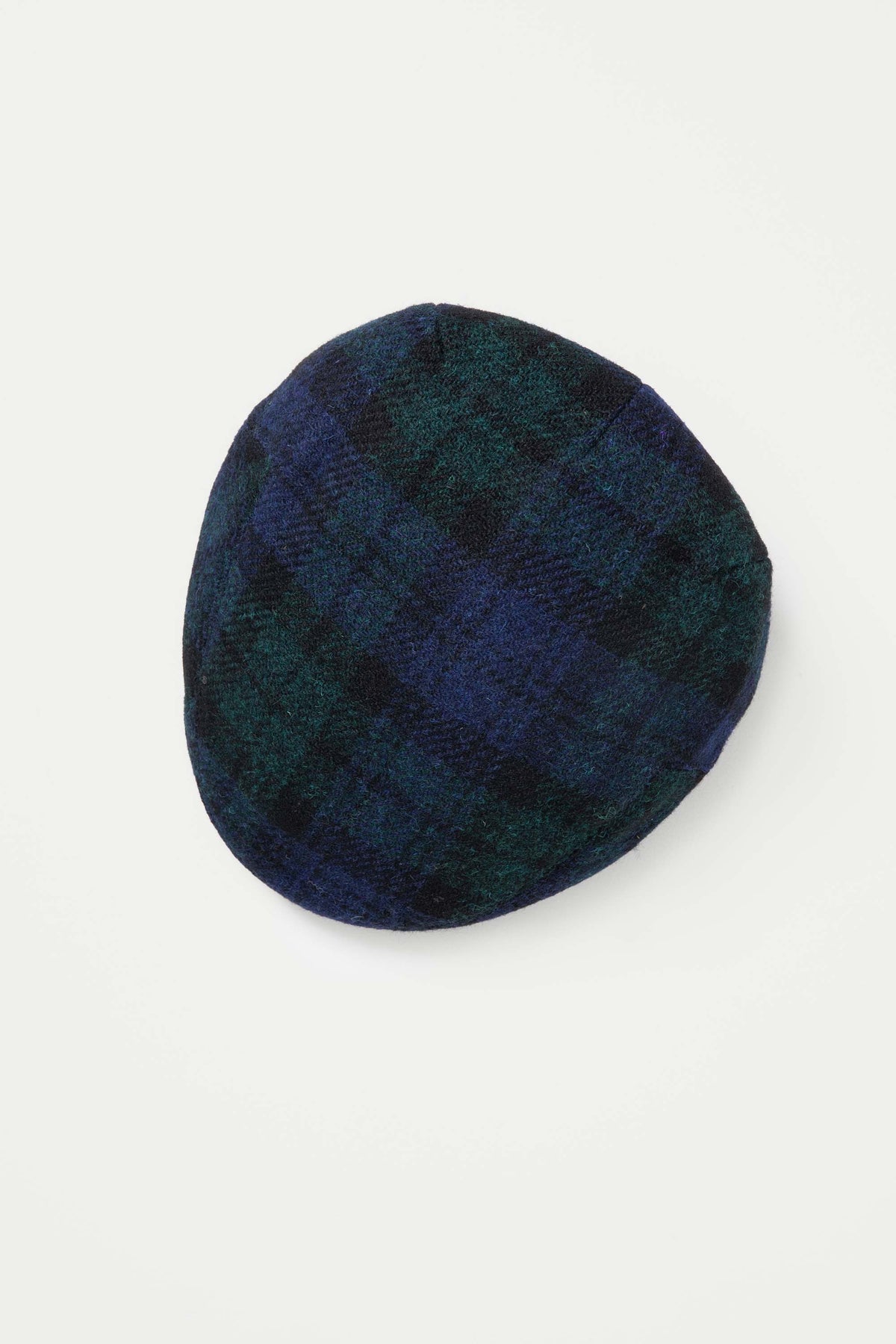 Harris Tweed Stornoway Cap in Blackwatch tartan, top-down view showing navy and green plaid wool pattern