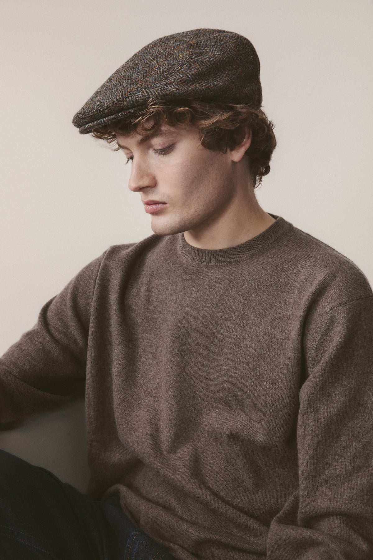 Harris Tweed Stornoway Cap in brown check herringbone worn by model, classic flat cap style with stitched peak