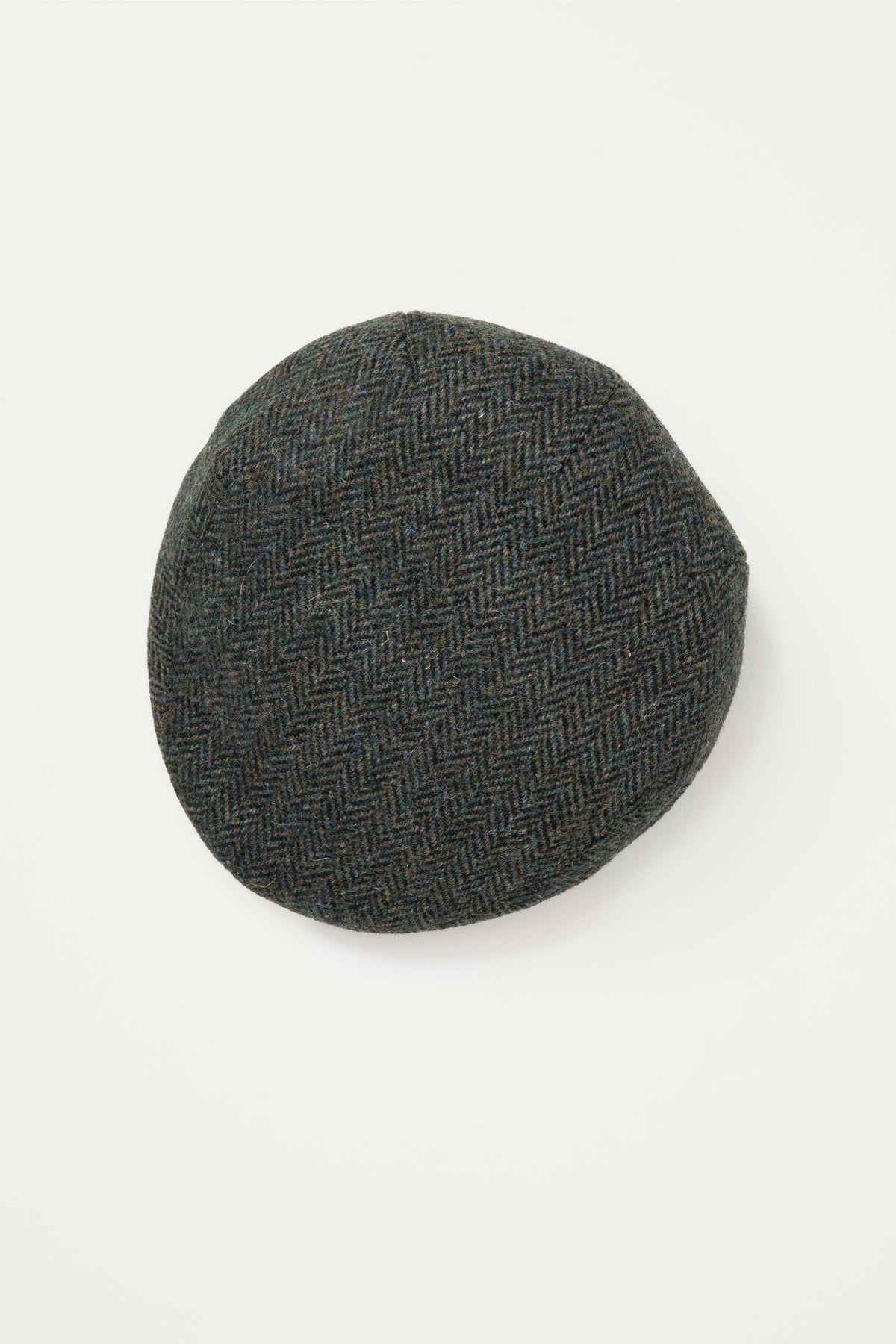 Harris Tweed Stornoway Cap in dark green herringbone, top-down view showing the rounded crown and tweed weave pattern