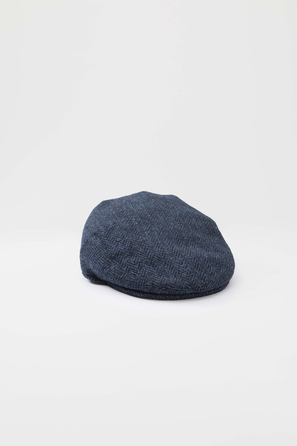 Harris Tweed Stornoway Cap in dark navy herringbone, rear three-quarter view showing the rounded crown and flat profile