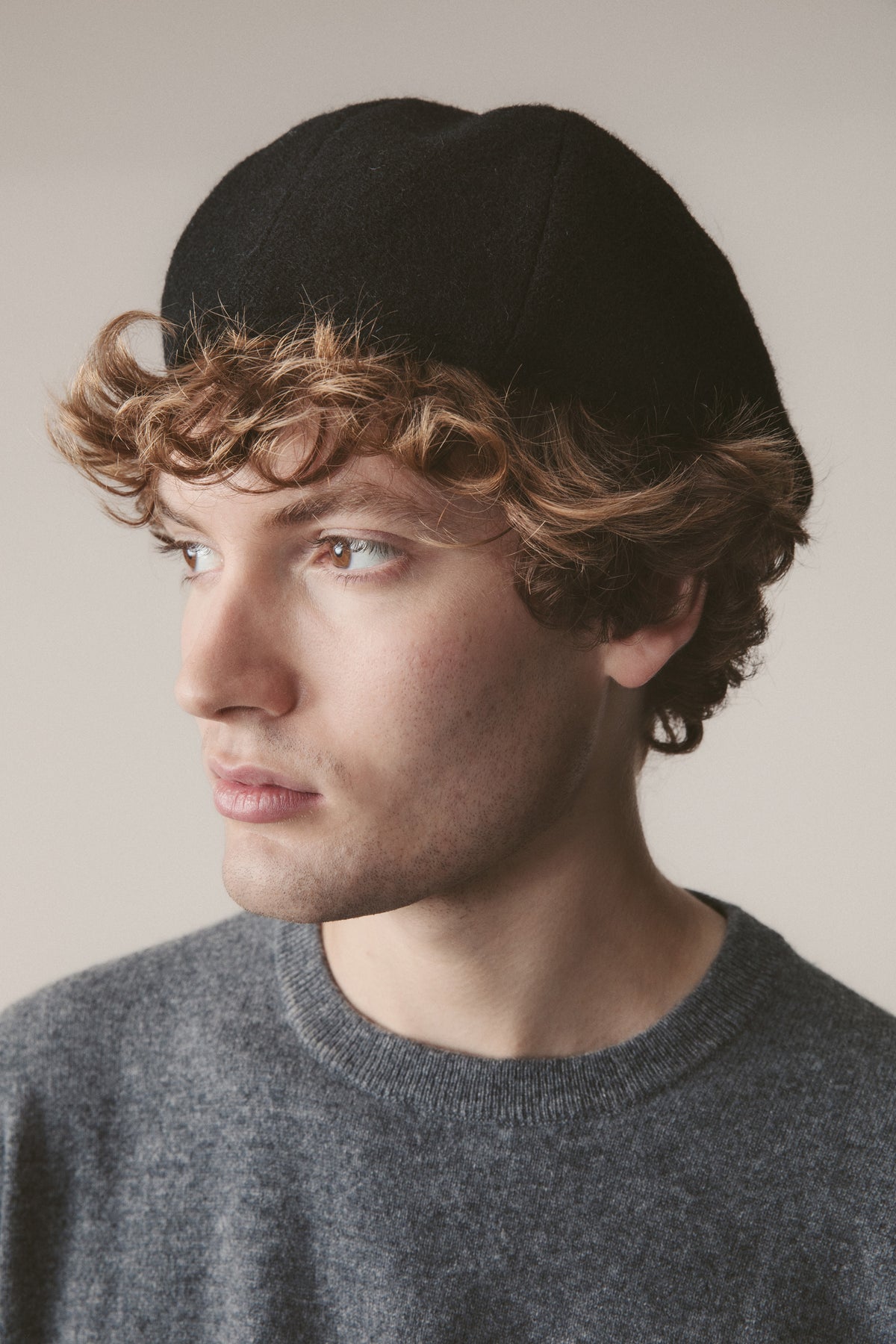 Harris Tweed Stornoway Cap in plain black twill, worn as a flat cap style, shown in three-quarter profile on a model