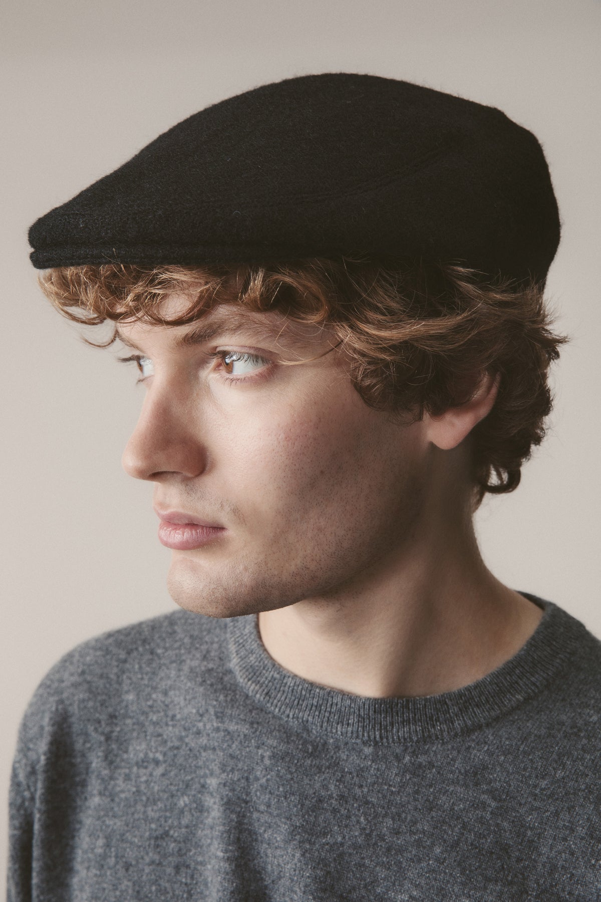 Harris Tweed Stornoway Cap in Plain Black Twill worn by model, three-quarter profile view showing flat cap fit and silhouette