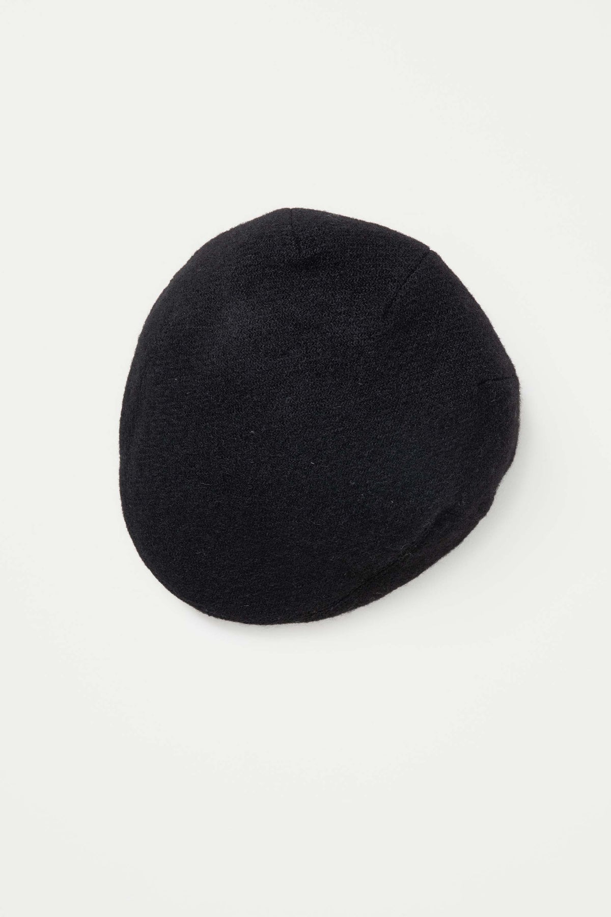 Harris Tweed Stornoway Cap in plain black twill, top-down view showing the rounded crown and panelled construction