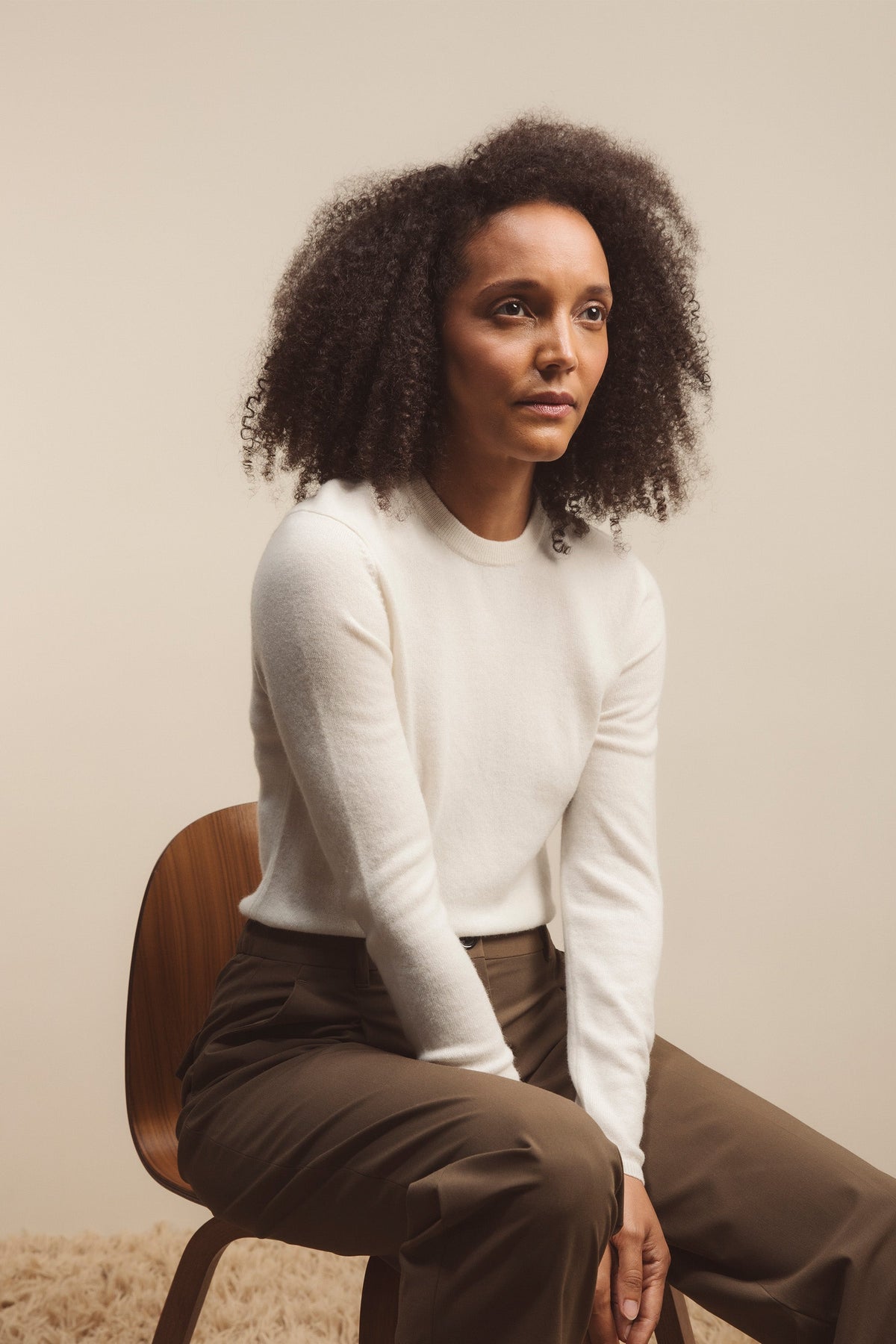 Women's Cashmere Crew Neck Jumper in Soft Cream, slim-fit 100% cashmere knit with ribbed neckline, styled seated