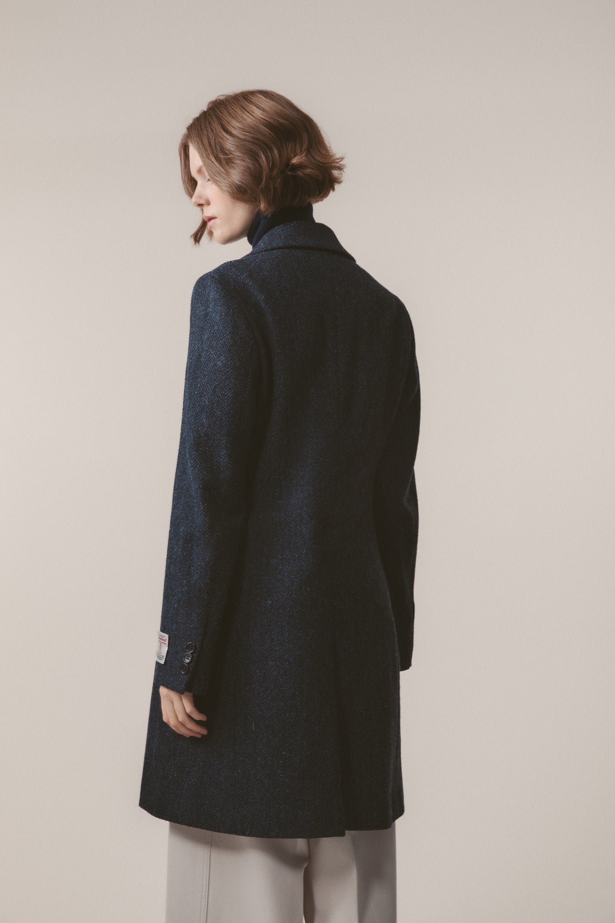 Back view of Women's Harris Tweed Melody Coat in dark navy blue herringbone, showing clean tailored silhouette and cuff button detail