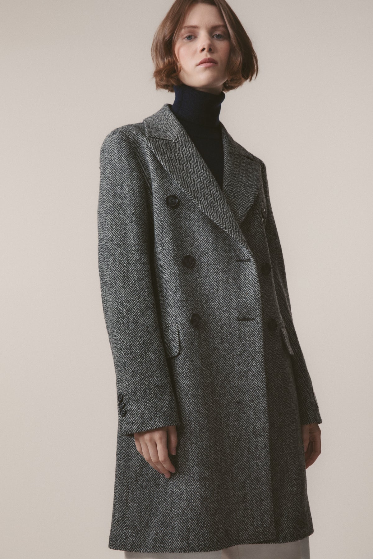 Women's Harris Tweed Melody Coat in light grey herringbone, front three-quarter view showing double-breasted button closure and wide lapels