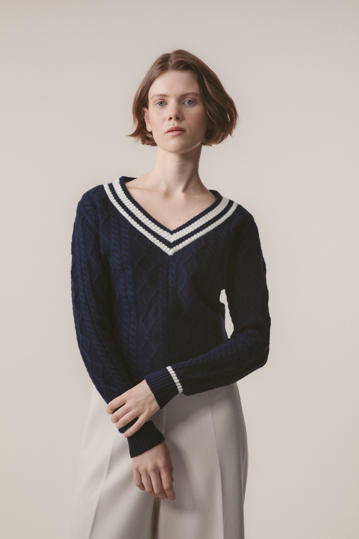 Model wearing Women's Cashmere Cricket Style Jumper in navy with cream striped V-neck and cuffs, showing cable-knit texture detail