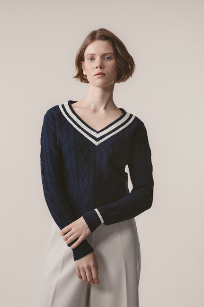 Model wearing Women's Cashmere Cricket Style Jumper in navy with cream striped V-neck and cuffs, showing cable-knit texture detail