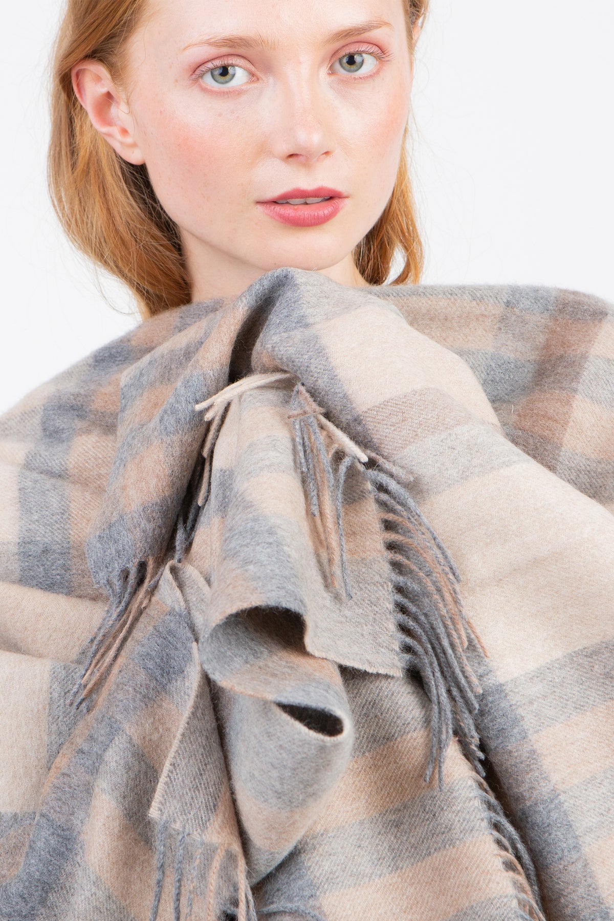 Close-up of Tartan 2 Cashmere Wrap in Natural worn by model, showing soft check pattern and fringed edges in grey and beige tones