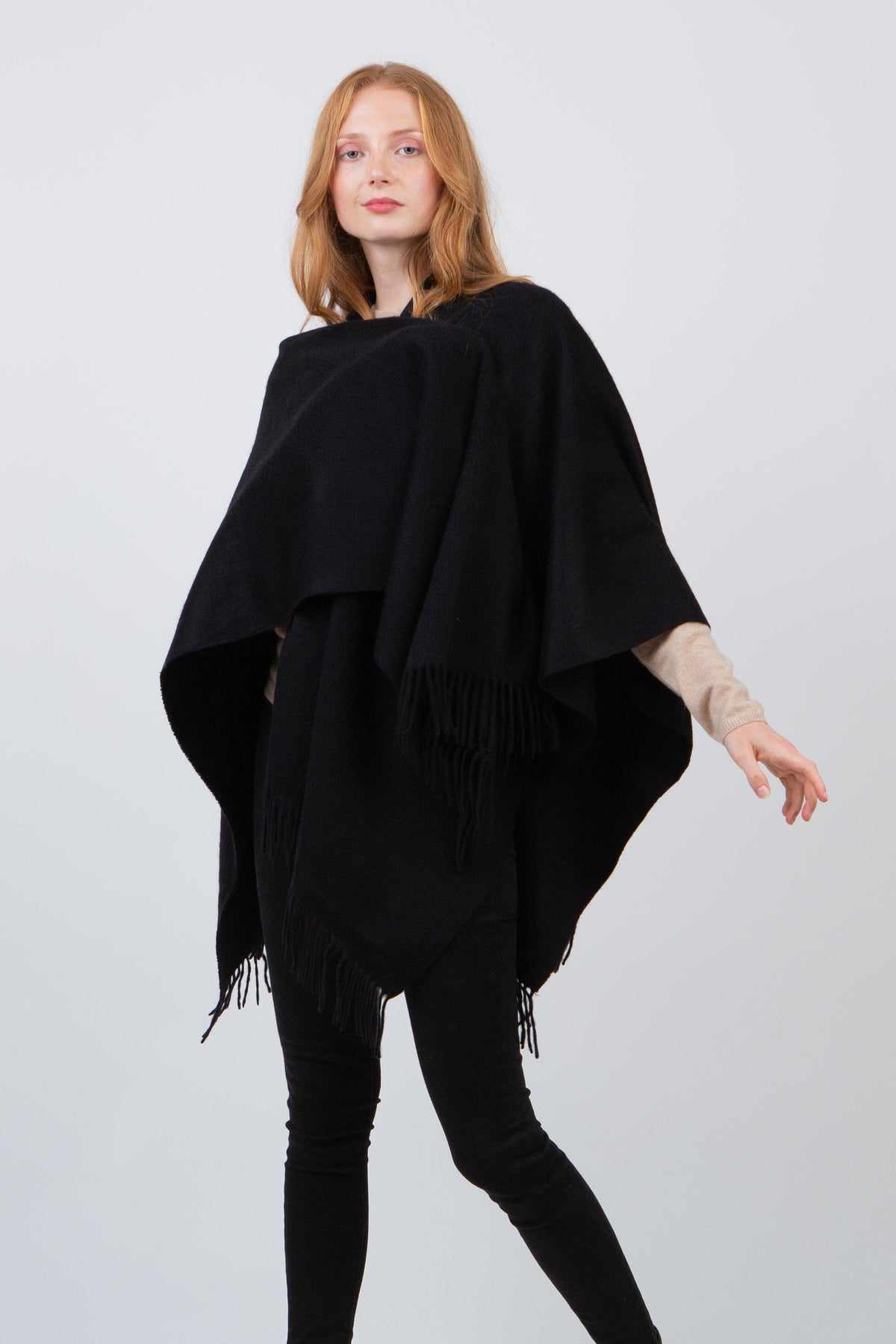 Solid Cashmere Wrap in Black with fringed edges, worn draped over shoulders as a layering piece over a beige sweater