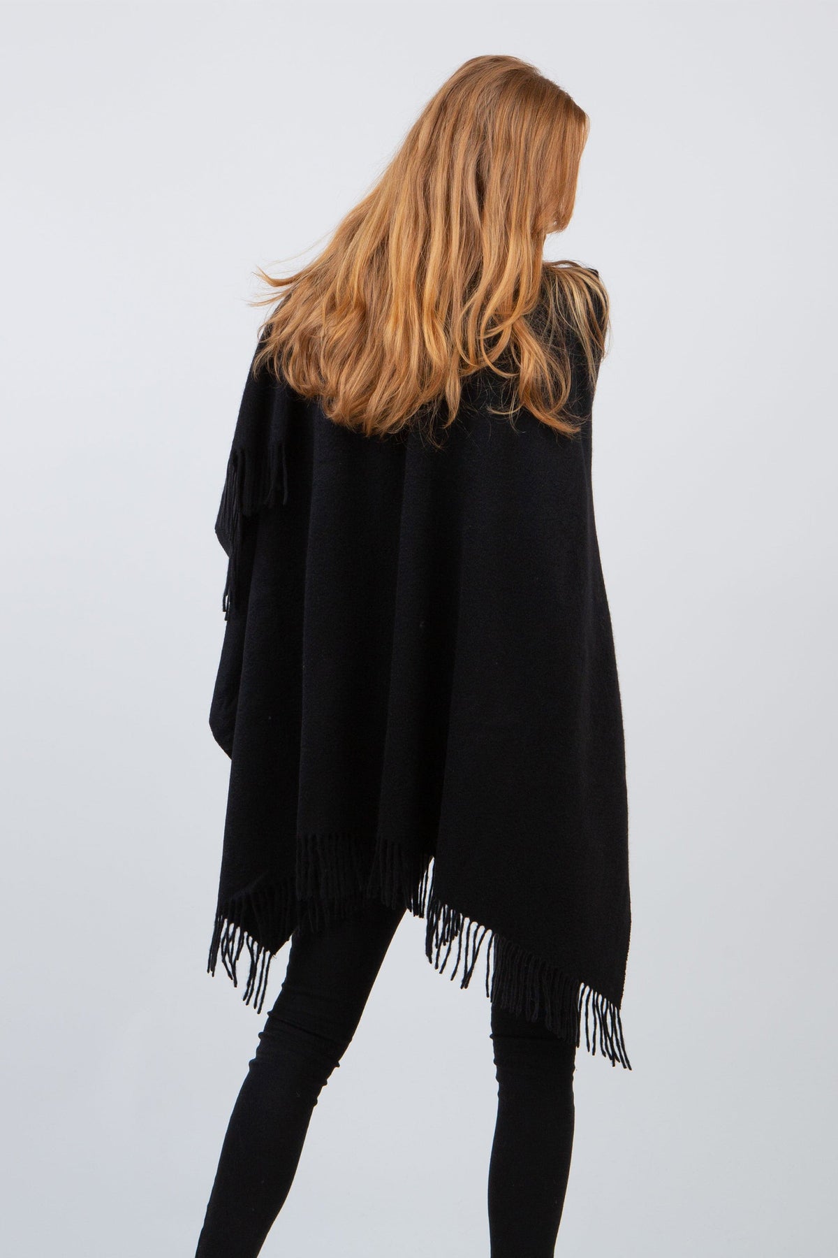 Back view of the Solid Cashmere Wrap in black, showing the full drape and fringed hem detail on a model