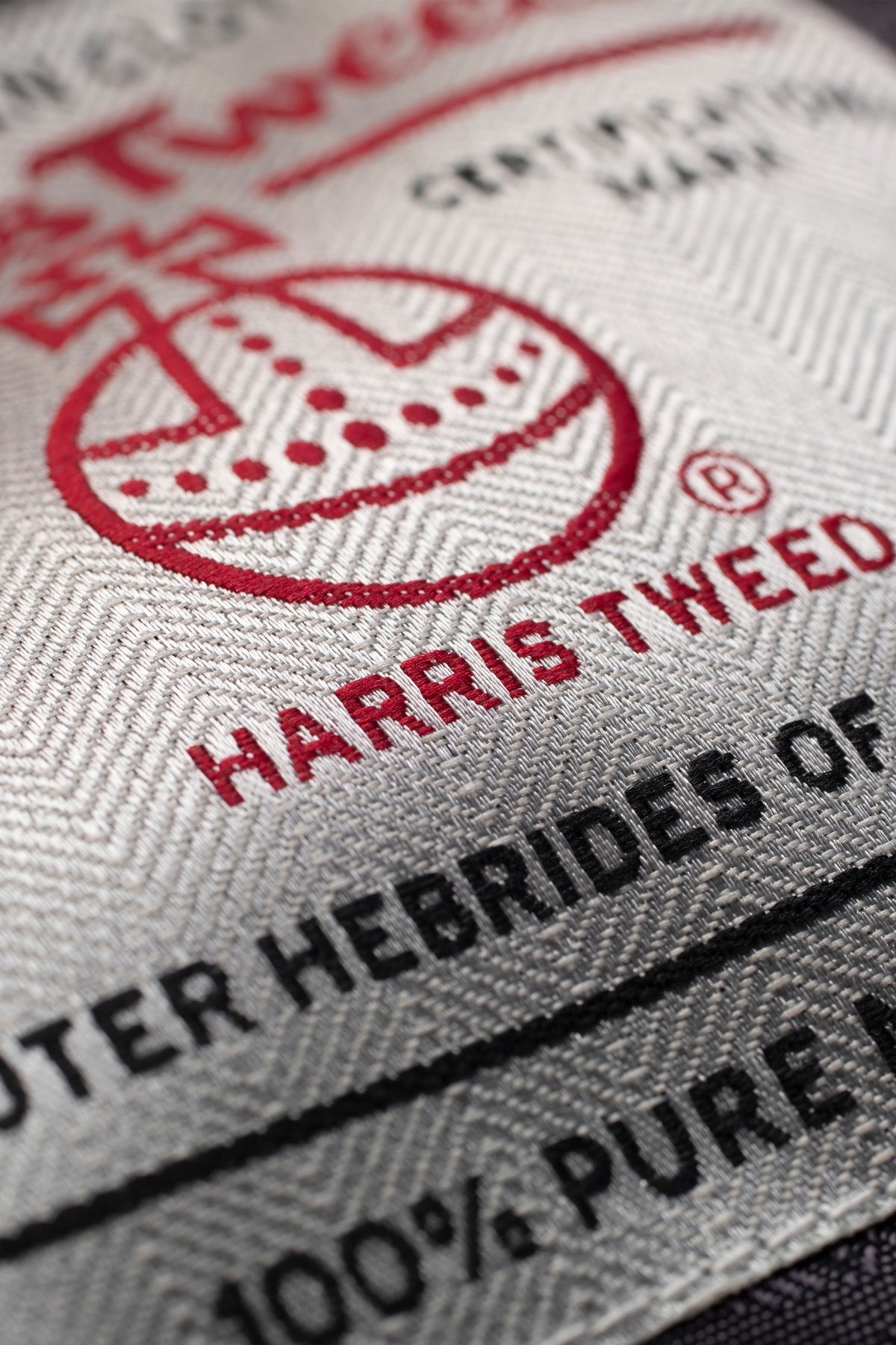 Close-up of Harris Tweed certification label on Men's Harris Tweed Bomber Jacket - Dogstooth, showing the Orb trademark and 100% pure wool mark