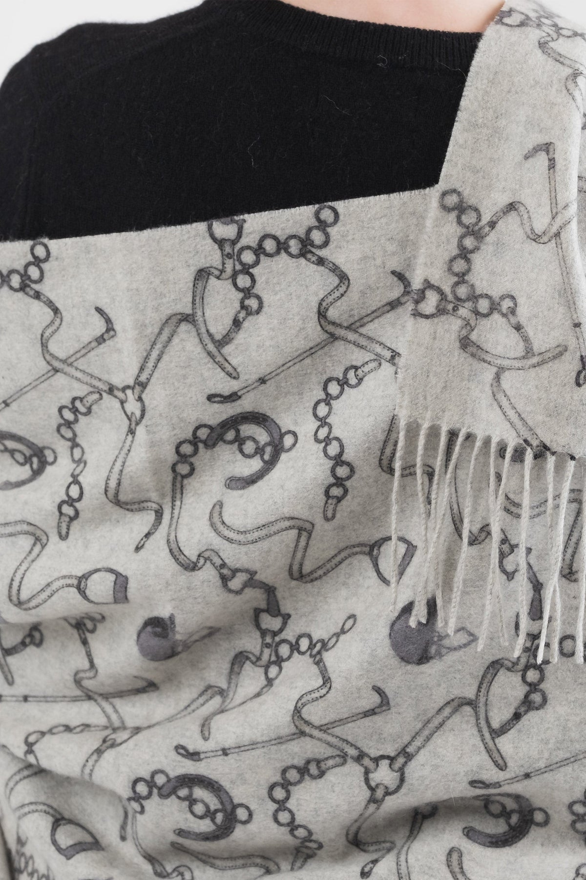 Close-up of Equestrian Cashmere Double Sided Stole in grey showing chain and bridle print detail with fringed edge