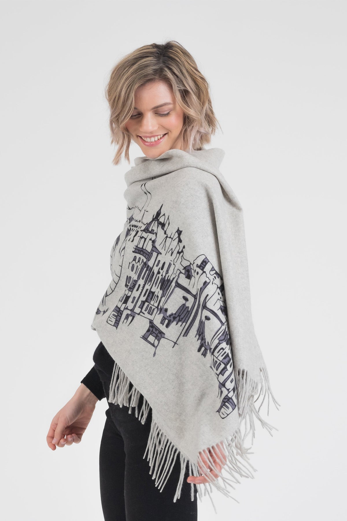 Skyline Cashmere Double Sided Stole in grey worn draped over shoulders, showing architectural cityscape print and fringed edges