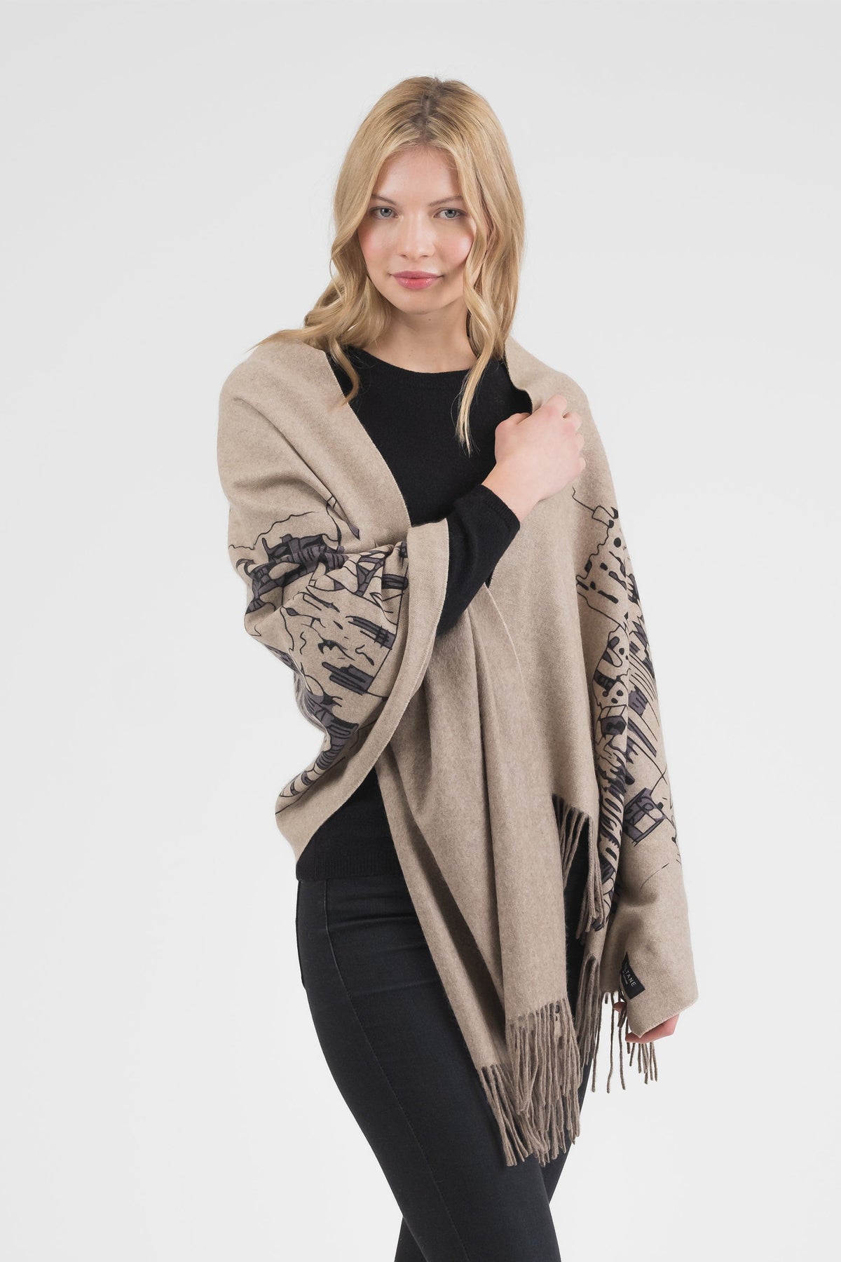 Model wearing Skyline Cashmere Double Sided Stole in Beige draped over shoulders, showing cityscape print and fringed edges