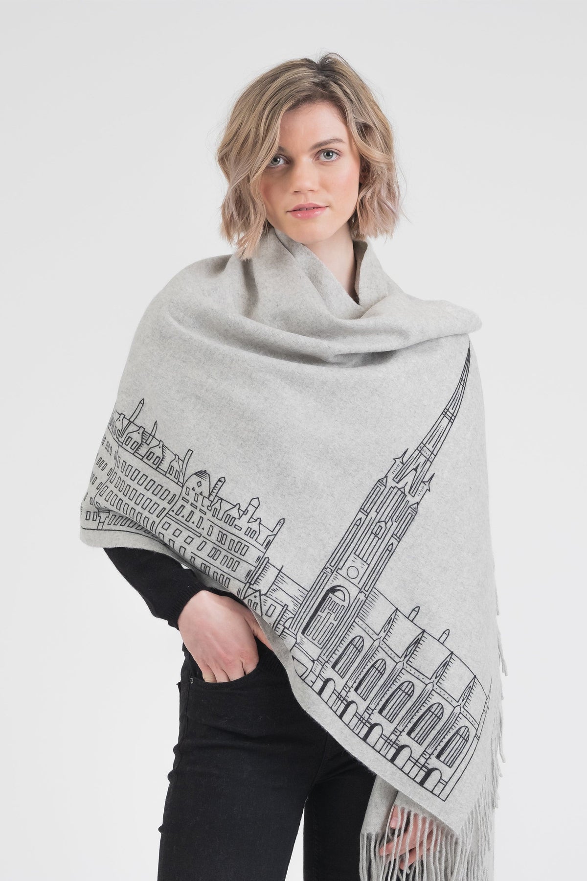 Royal Mile Cashmere Double Sided Stole in grey, worn as a wrap, featuring handprinted cityscape illustration with fringed ends